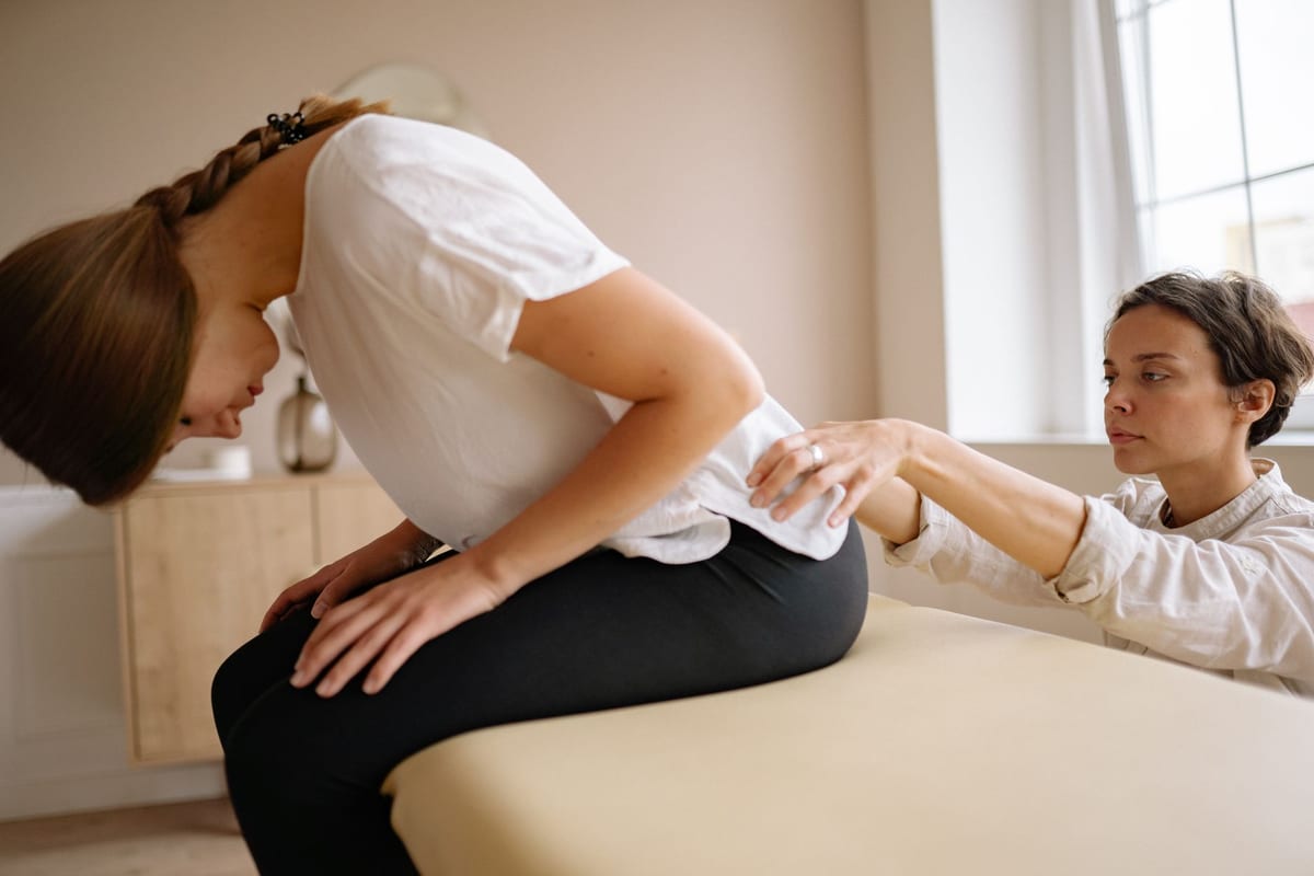 A clinician examining a seated patient's lower back