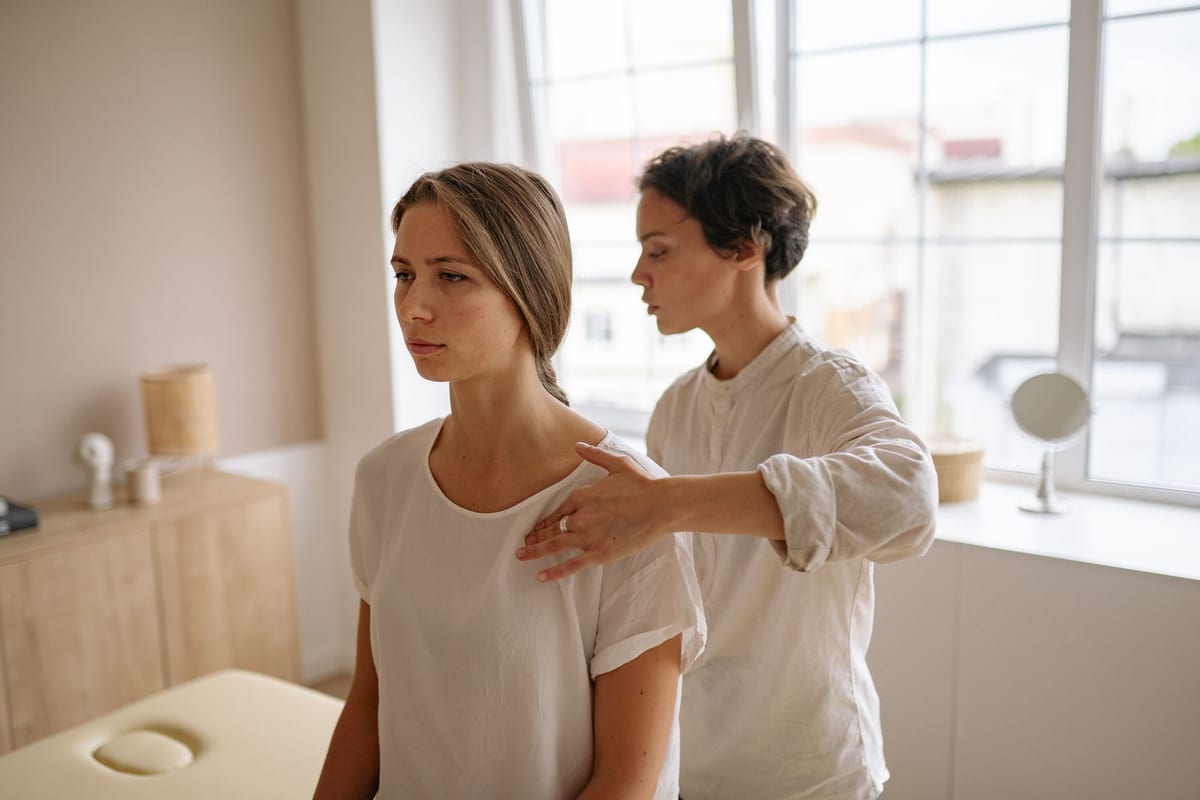 A clinician treating a patient's shoulder and neck while standing