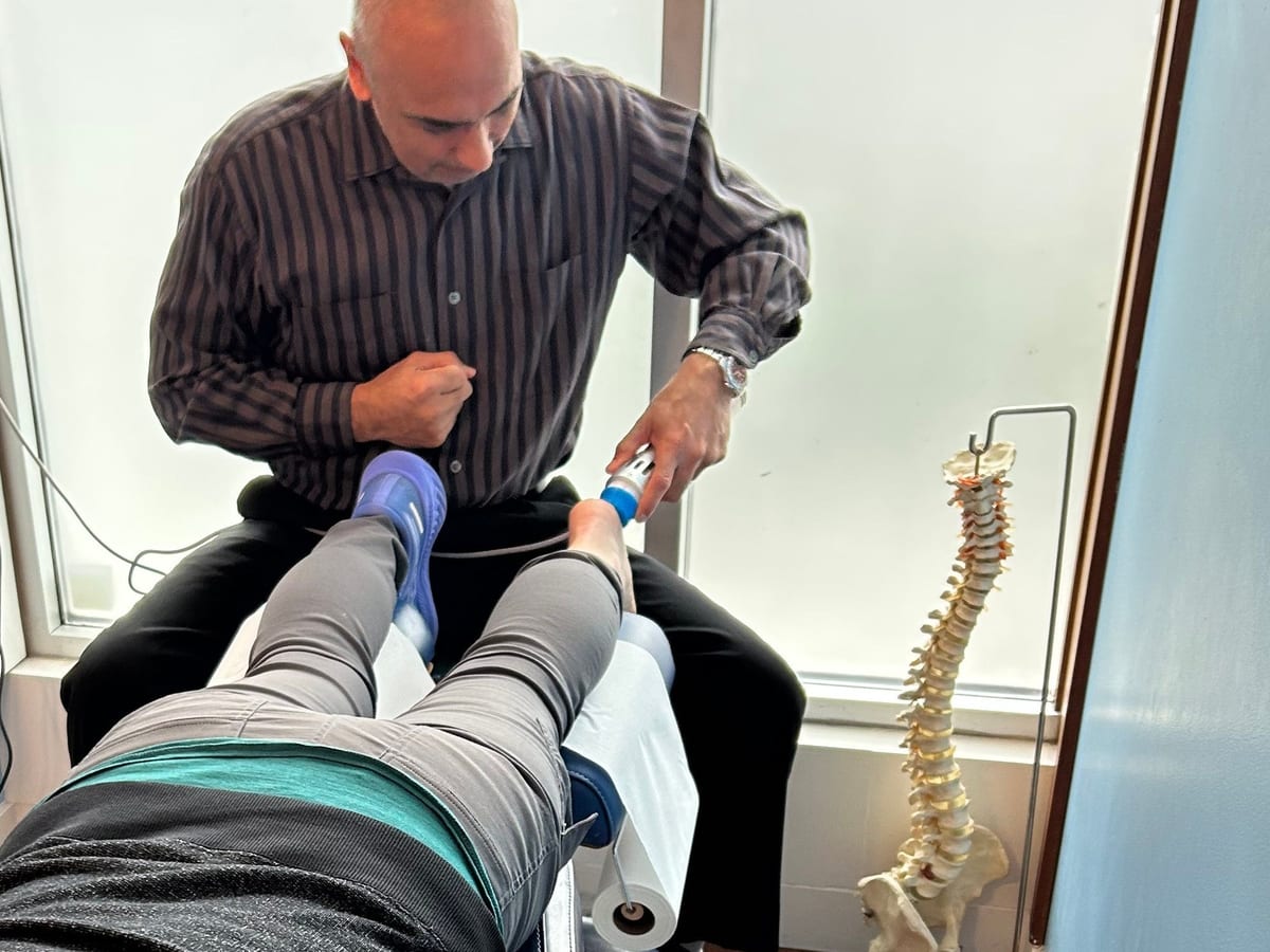 Dr. Madahar applying shockwave therapy to a patient's foot at the clinic